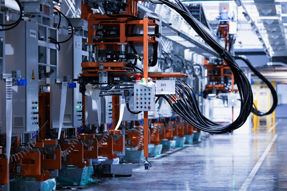 Productielijn in een fabriekshal met machines, kabelgeleiding en besturingen